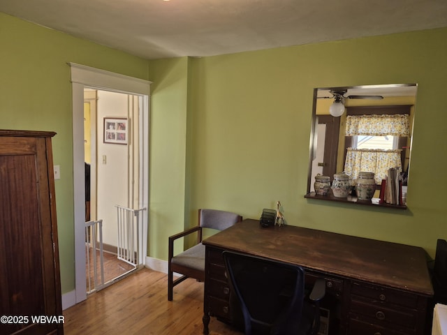 office space featuring baseboards, a ceiling fan, and wood finished floors