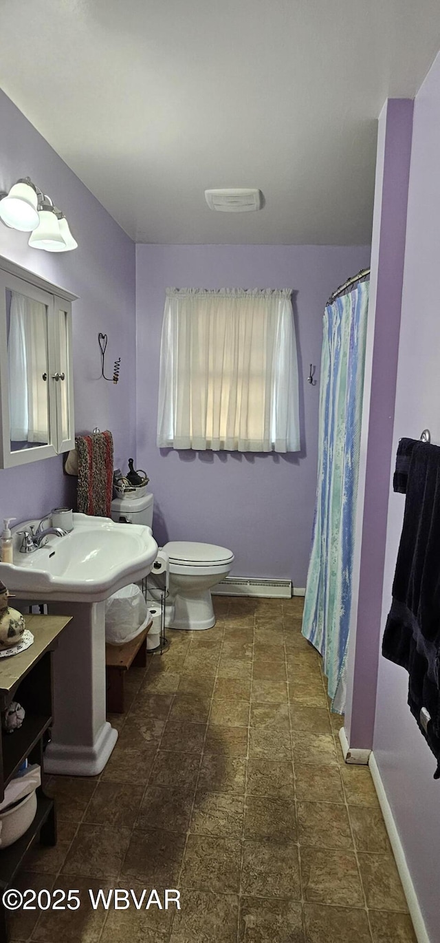 bathroom featuring a shower with curtain, sink, baseboard heating, and toilet