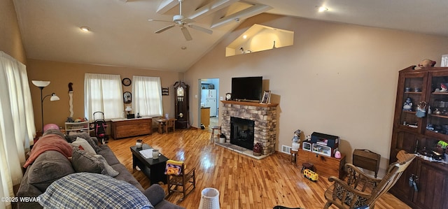 living room featuring ceiling fan, high vaulted ceiling, a fireplace, and light hardwood / wood-style floors