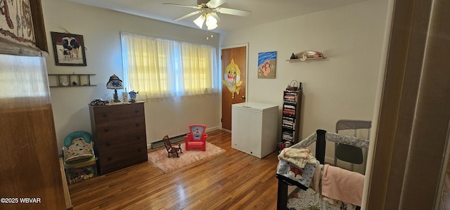 interior space with refrigerator, hardwood / wood-style floors, ceiling fan, and baseboard heating