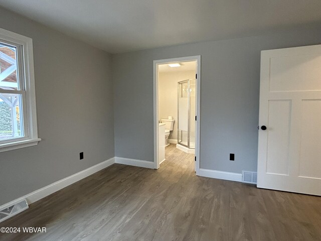 unfurnished bedroom with wood-type flooring and ensuite bathroom