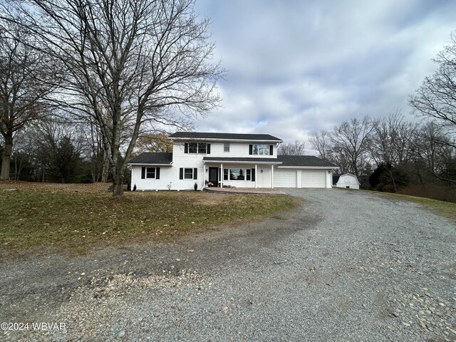 front of property with a garage, covered porch, and a front yard