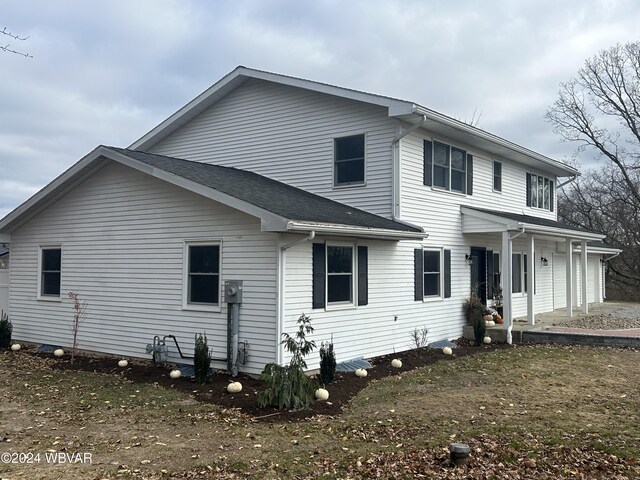 rear view of property with a porch, a yard, and a garage