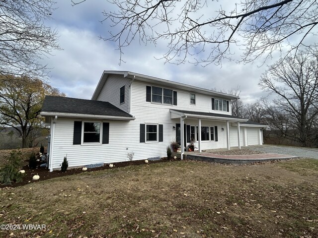 view of front of home featuring a garage, covered porch, and a front lawn