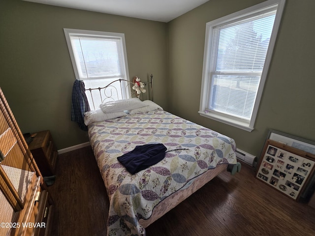 bedroom with baseboard heating, multiple windows, and dark hardwood / wood-style floors