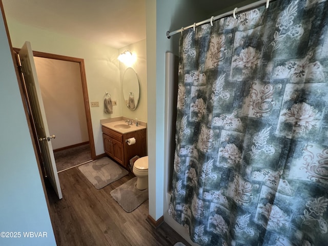 full bath featuring toilet, wood finished floors, a shower with shower curtain, baseboards, and vanity