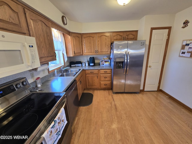 kitchen featuring a sink, stainless steel appliances, brown cabinets, and light wood-type flooring