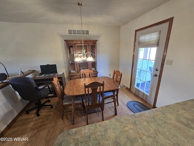 dining area with visible vents, an inviting chandelier, and wood finished floors