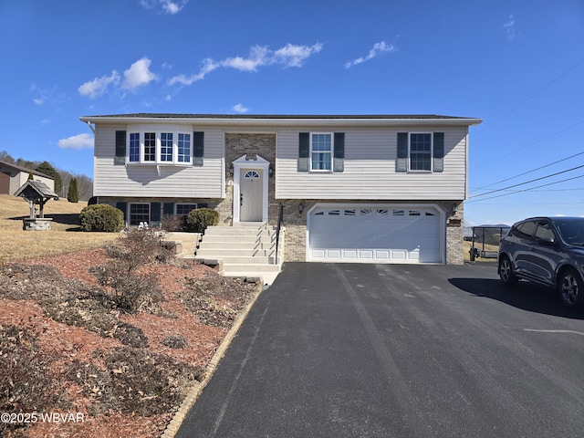 raised ranch featuring aphalt driveway and an attached garage