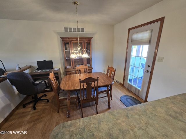 dining room featuring visible vents, wood finished floors, and a chandelier