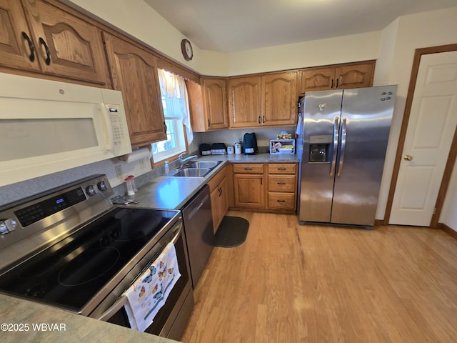 kitchen featuring brown cabinets, appliances with stainless steel finishes, light wood-type flooring, and a sink