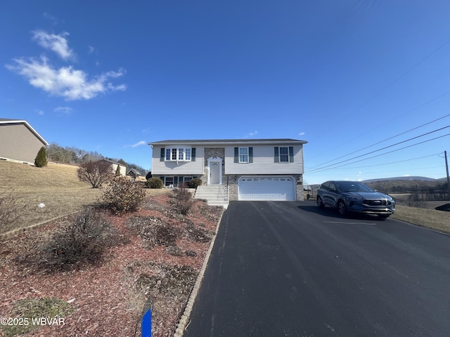 bi-level home featuring aphalt driveway and an attached garage