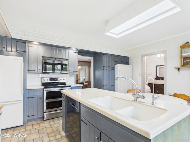 kitchen with appliances with stainless steel finishes, a sink, light countertops, gray cabinetry, and crown molding