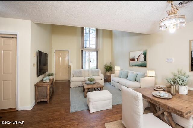 living room featuring dark hardwood / wood-style flooring, a textured ceiling, and a notable chandelier