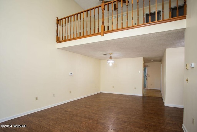 unfurnished living room with a textured ceiling, dark hardwood / wood-style flooring, and an inviting chandelier