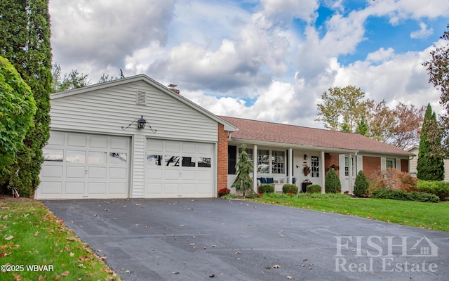 single story home featuring a garage, a front lawn, aphalt driveway, and brick siding