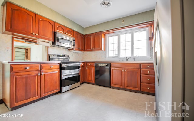 kitchen with stainless steel appliances, a sink, visible vents, light countertops, and light floors