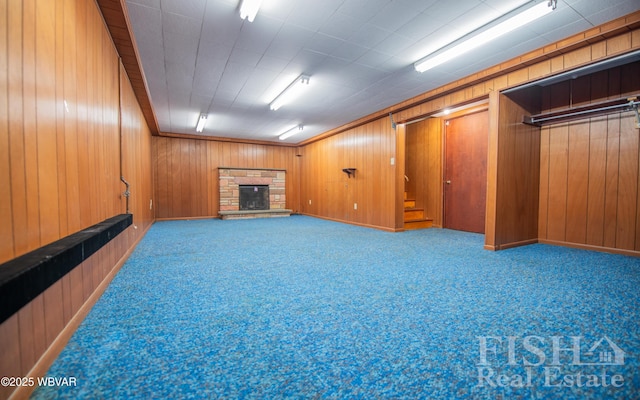 finished below grade area with stairway, carpet, a stone fireplace, and wooden walls