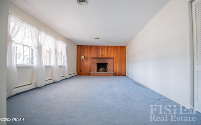 unfurnished living room with light carpet, a brick fireplace, visible vents, and wooden walls