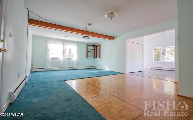 spare room featuring beamed ceiling, baseboard heating, and a healthy amount of sunlight