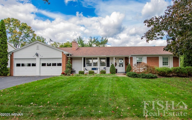 single story home featuring driveway, a front lawn, and brick siding