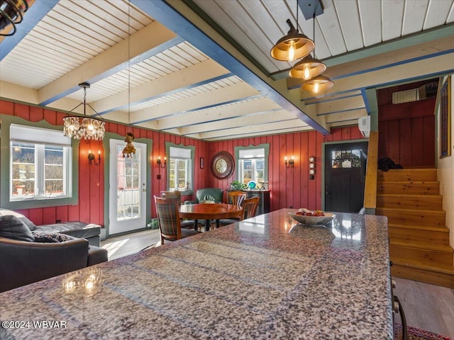 kitchen featuring wooden walls, pendant lighting, beamed ceiling, hardwood / wood-style floors, and a chandelier