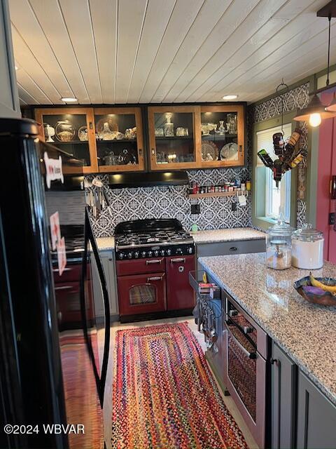 kitchen with wooden ceiling, decorative light fixtures, light stone countertops, and tasteful backsplash