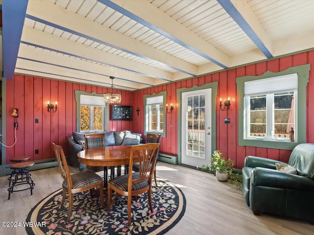 dining room with beam ceiling, light wood-type flooring, a baseboard heating unit, and a notable chandelier