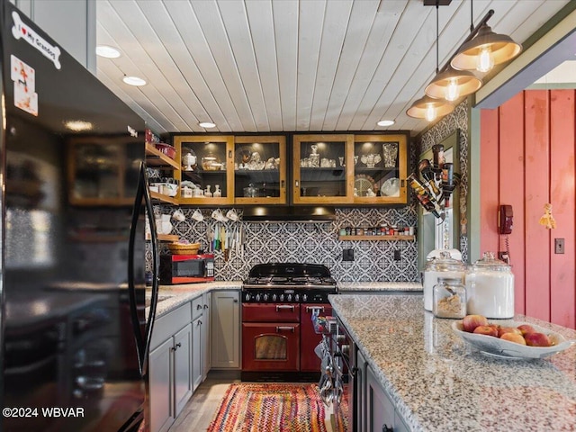 kitchen featuring backsplash, black appliances, light stone counters, decorative light fixtures, and dark hardwood / wood-style flooring