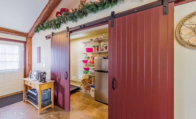 interior space with a barn door and vaulted ceiling with beams