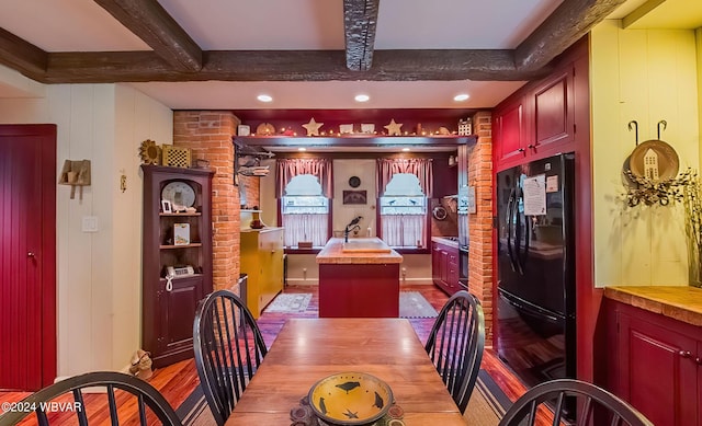 dining room with wooden walls, sink, beamed ceiling, and light wood-type flooring