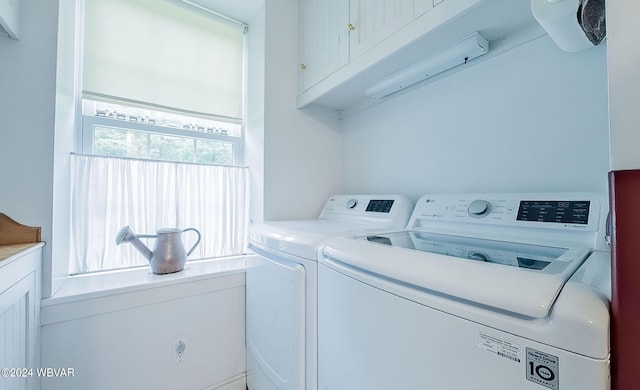 clothes washing area with cabinets and washing machine and dryer