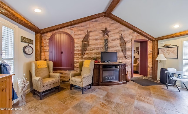 living area with vaulted ceiling with beams and brick wall