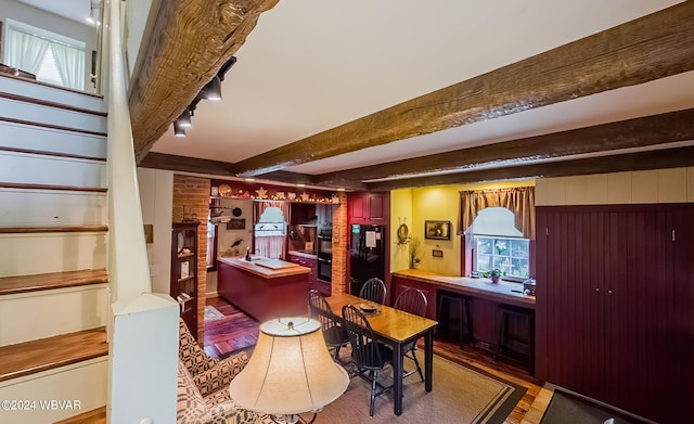 kitchen featuring wood walls, beamed ceiling, black appliances, and light wood-type flooring