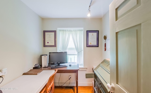 office space with light wood-type flooring and rail lighting