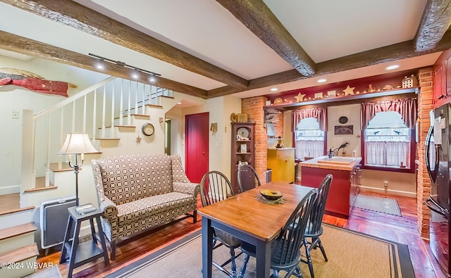 dining area featuring hardwood / wood-style floors, beamed ceiling, and sink