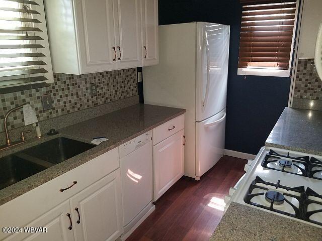 kitchen with white cabinetry, white appliances, and backsplash