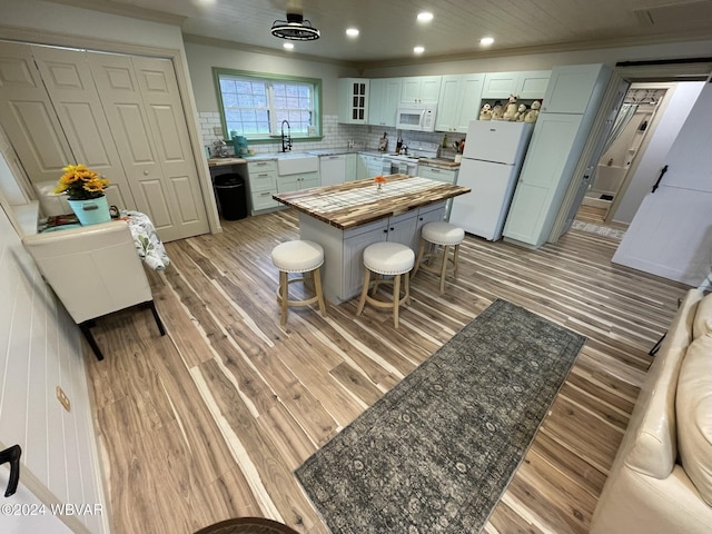 kitchen with decorative backsplash, white appliances, crown molding, sink, and light hardwood / wood-style floors