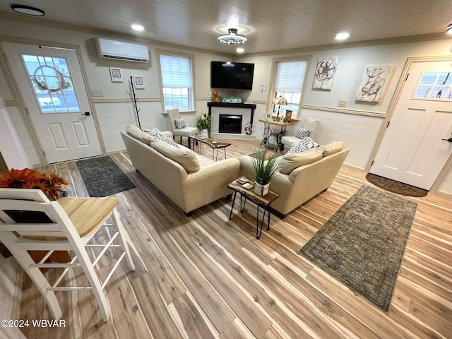 living room with wood-type flooring, ornamental molding, and a wall unit AC