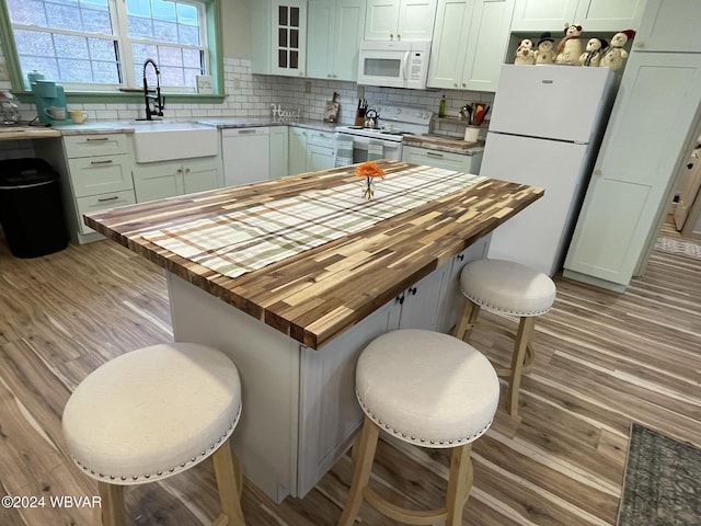 kitchen with a breakfast bar, white appliances, butcher block counters, and sink