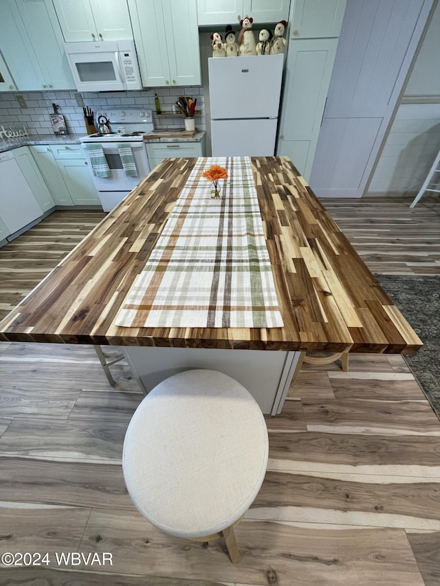 kitchen with hardwood / wood-style flooring, decorative backsplash, white appliances, and butcher block counters