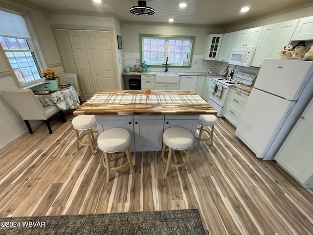 kitchen with wooden counters, white appliances, a kitchen island, light hardwood / wood-style flooring, and white cabinetry