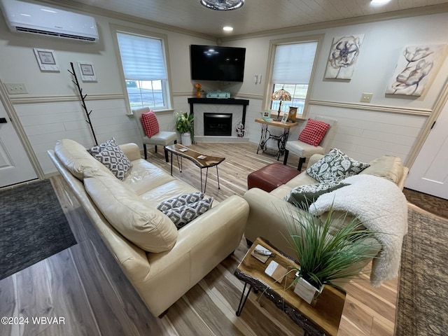 living room with a high end fireplace, wood-type flooring, a wall mounted air conditioner, and ornamental molding