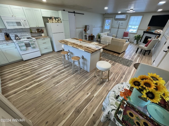 kitchen with butcher block countertops, a barn door, white cabinetry, and white appliances