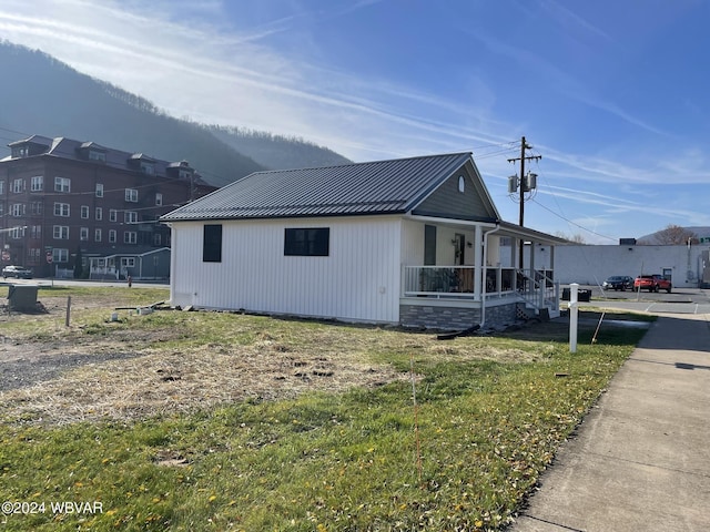 view of side of property with a lawn and covered porch