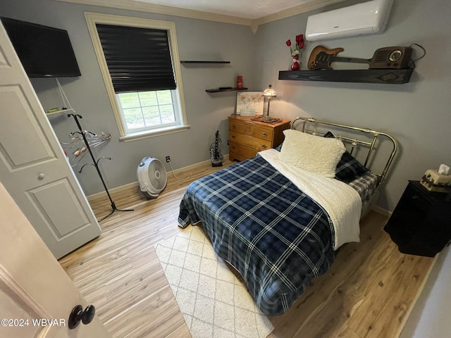 bedroom with light wood-type flooring, crown molding, and a wall mounted AC