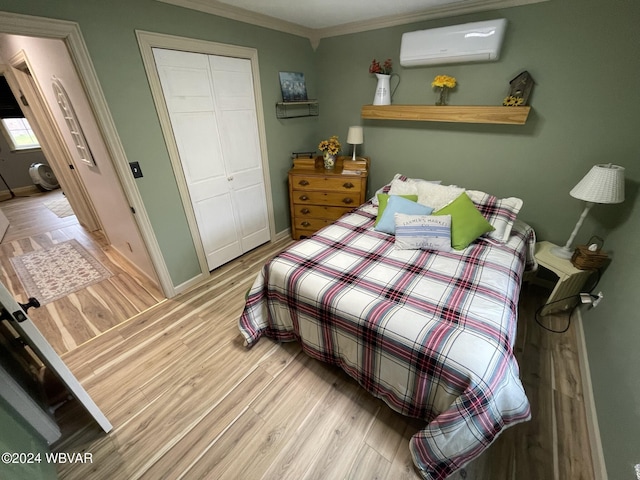 bedroom with ornamental molding, light hardwood / wood-style flooring, a wall unit AC, and a closet