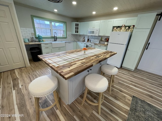 kitchen with sink, wooden counters, white appliances, a breakfast bar, and white cabinets