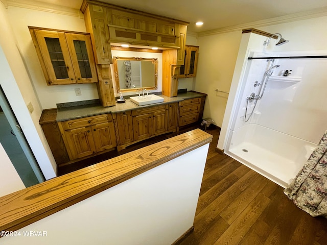 bathroom with hardwood / wood-style floors, vanity, a shower, and crown molding