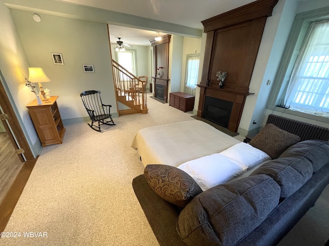 carpeted living room featuring a fireplace and ceiling fan